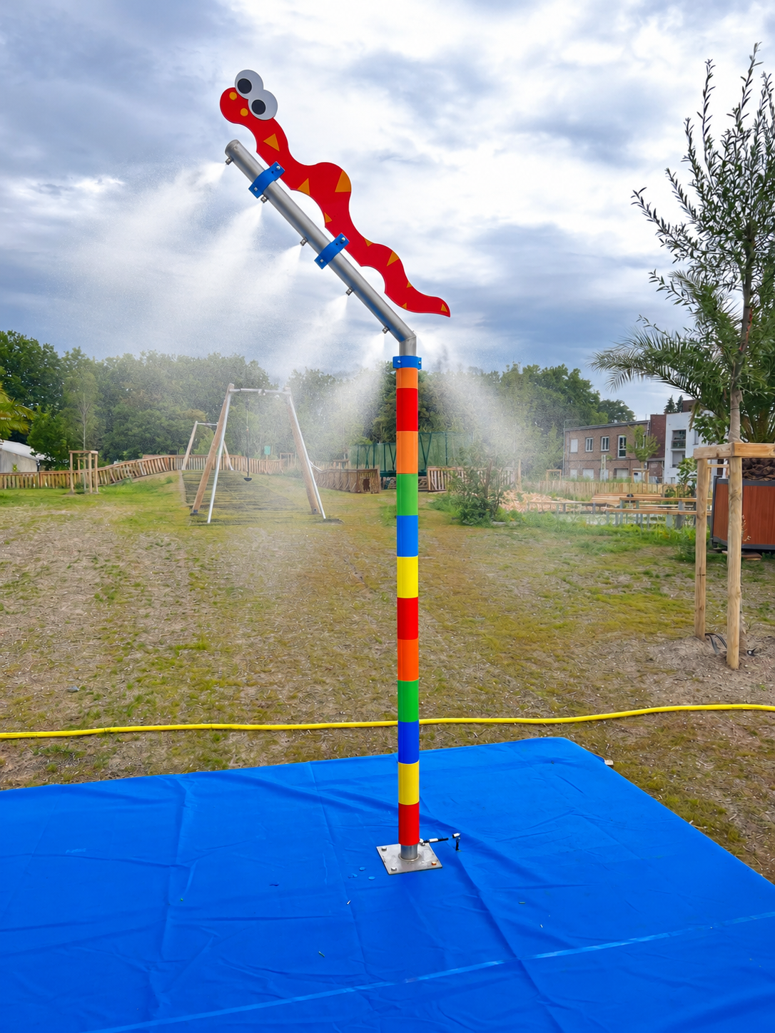 Poteau de brumisation décoré au premier plan sur l'aire de jeux