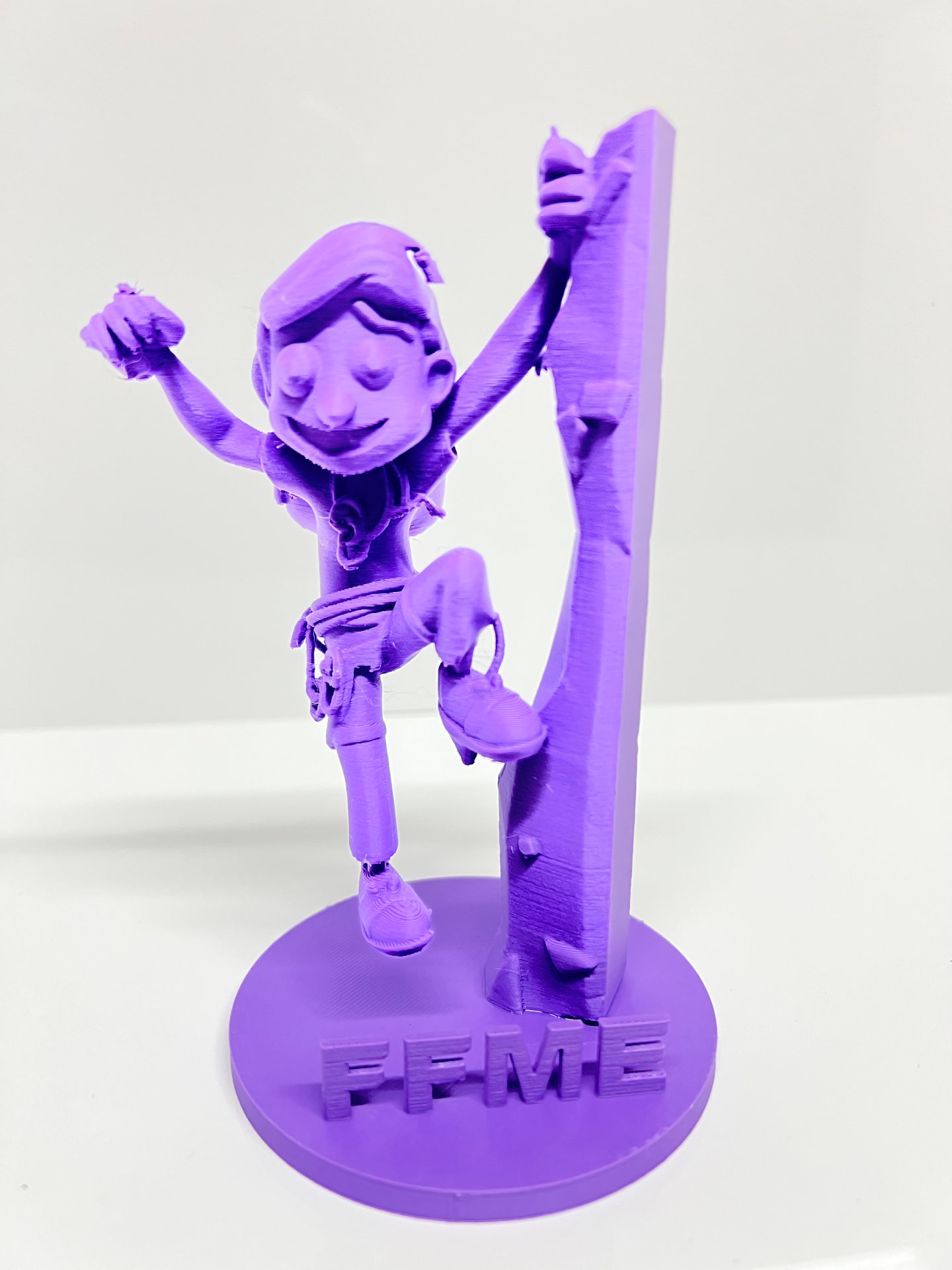 Figurine du grimpeur imprimée en 3D, violette, sur son socle FFME
